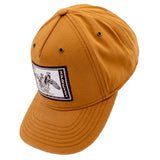 Side of a light brown cap with a white and brown stamp patch on the front.