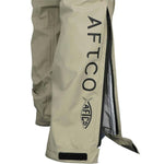 Close up of the leg of a beige fishing pants with AFTCO branding on the calf, with the side unzipped. 