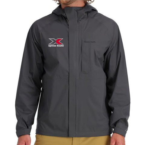 A man wearing a grey rain jacket with the simms logo in black on the left chest and the xpress logo in red and white on the right chest.