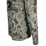 Close-up of a side pocket on a long-sleeve performance shirt with a multi-tonal camouflage pattern in beige, olive green, and slate blue. 